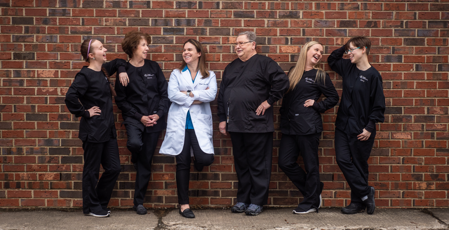 the Bass Dentistry team hanging out in front of a brick wall, in work attire