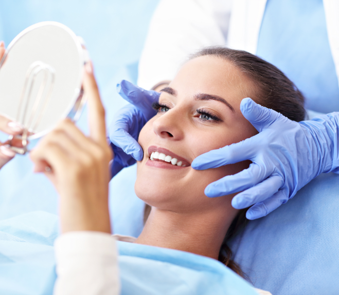 Close up of woman looking at her straight white teeth in a mirror with the help of her cosmetic dentist