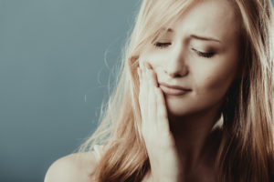 woman holding mouth in pain